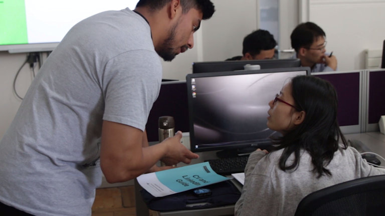 Teacher explaining something to a female student at a computer