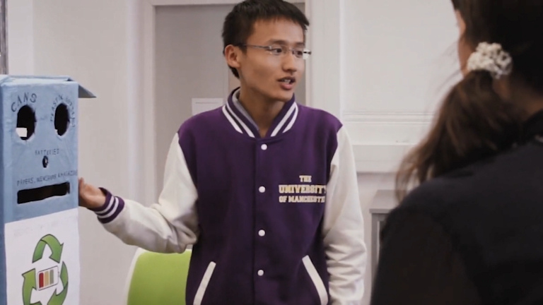 Chinese Manchester student indicating a prototype of a recycling bin