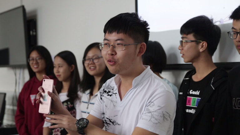 Chinese student demonstrating an idea on his mobile phone 